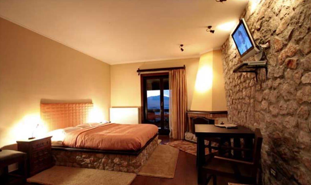 Η Junior Suite με αναμμένο τζάκι και πόρτα στο μπαλκόνι